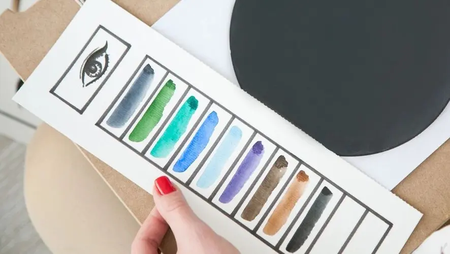 A woman is holding the colors of her paint set.