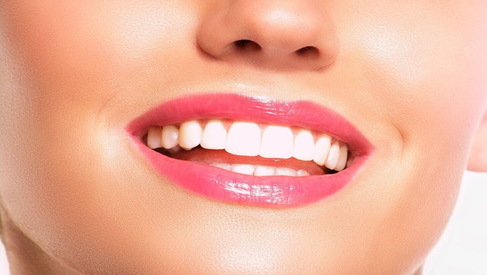 A close up of the teeth of a woman with pink lips